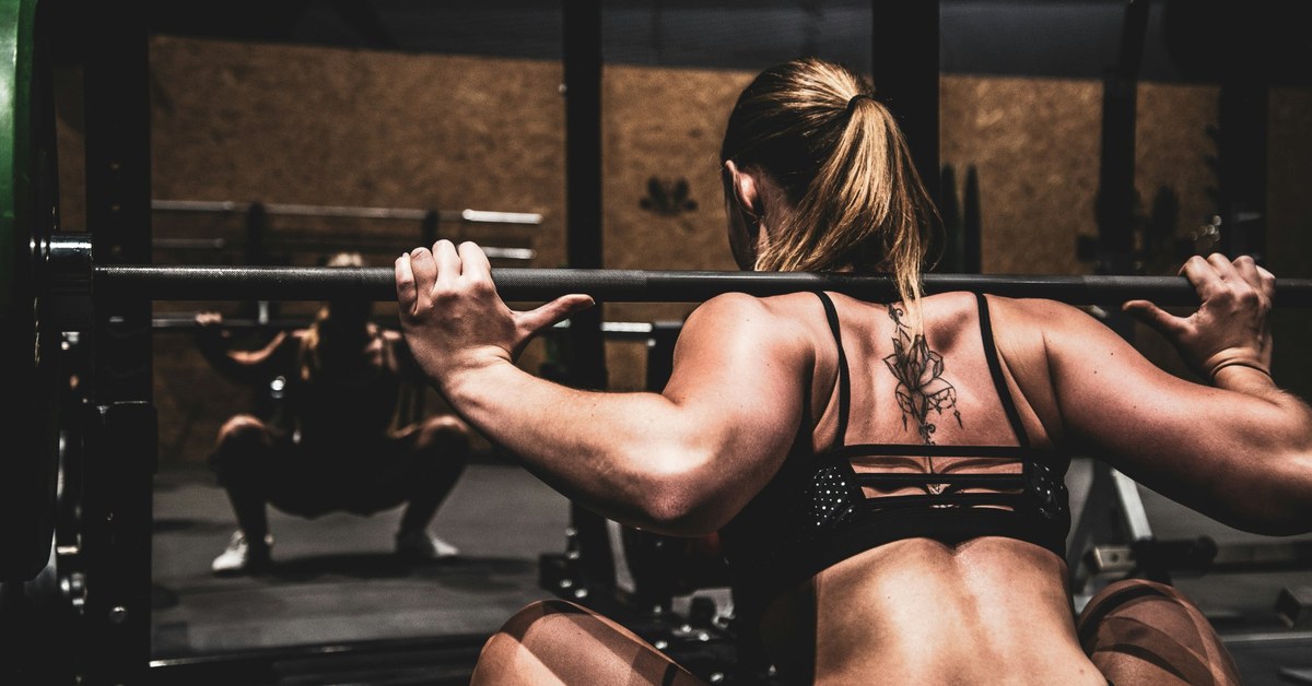 Woman with a barbell on her shoulder at the bottom of a squat